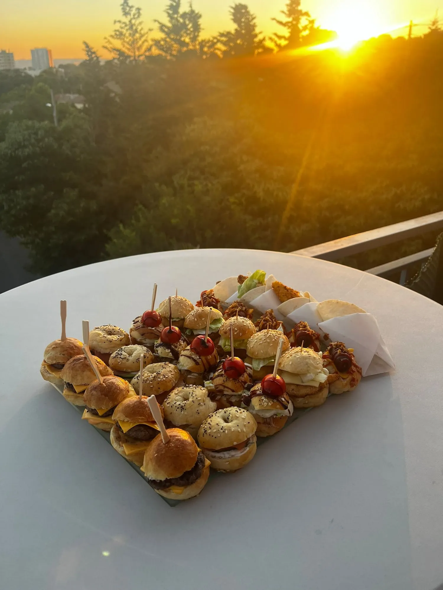 Plateau de mini-burgers présenté en terrasse au coucher du soleil